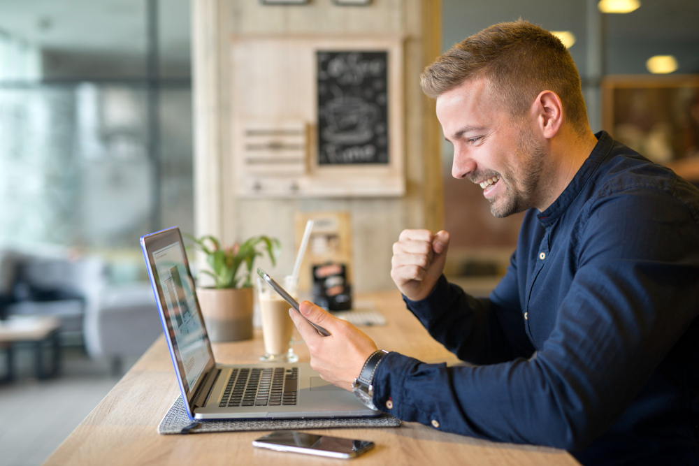 Happy man using laptop representing resilient entrepreneur